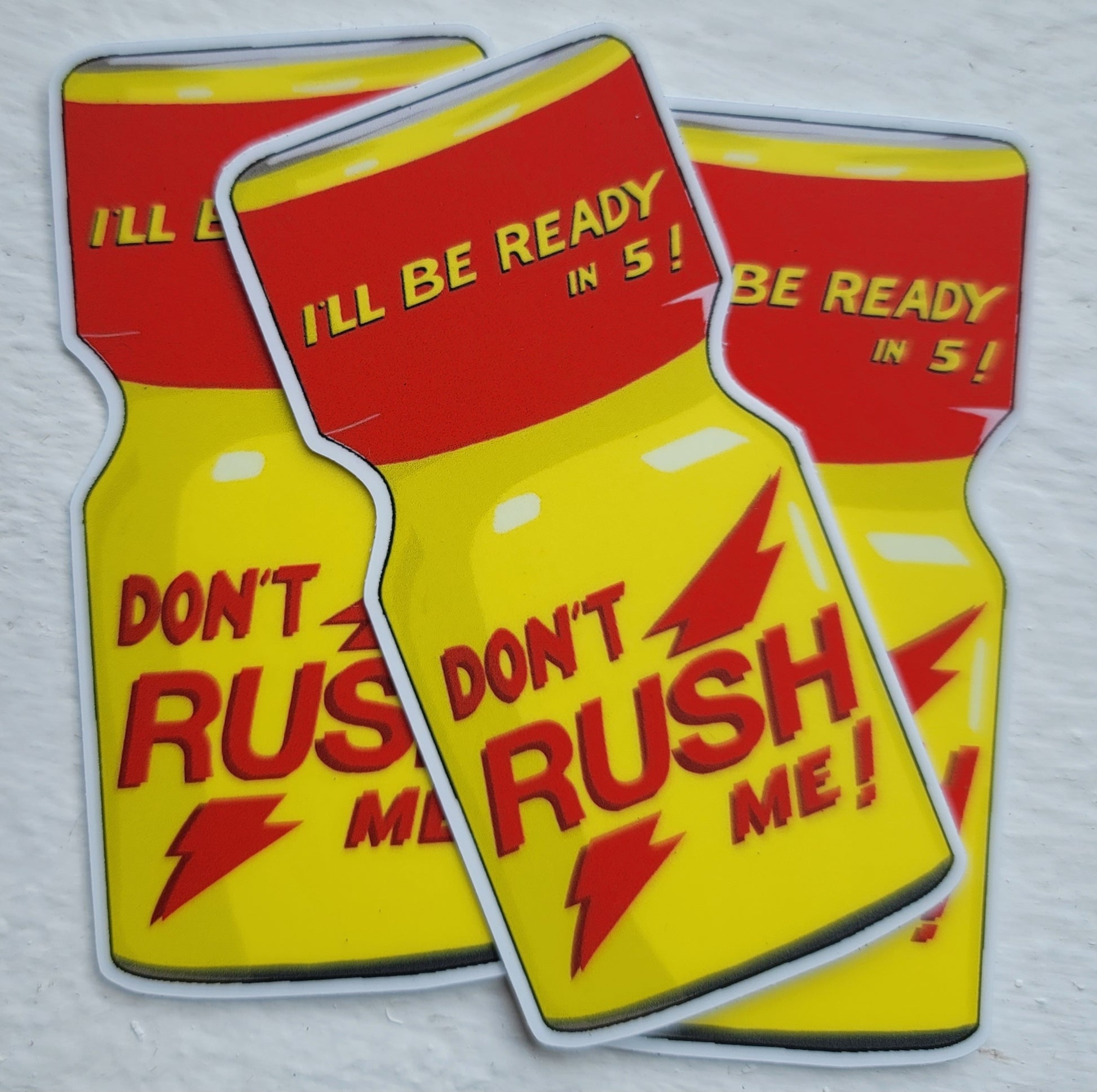 three bright yellow and red stickers that say "Dont Rush Me!" and are shaped like a bottle of Rush