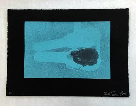 Light blue silkscreen print of a baby sleeping in an open guitar case, printed on black paper. This is the artist as an actual baby.