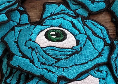 Embroidered patch of blue rose with eyeball in center