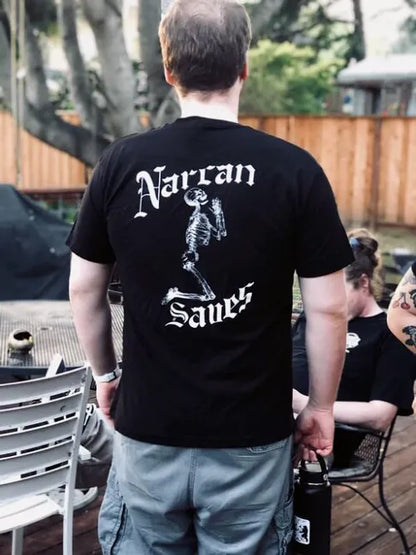 A man is standing outside facing away from the viewer. He is wearing the Narcan Saves shirt showing off the larger, full-back print.