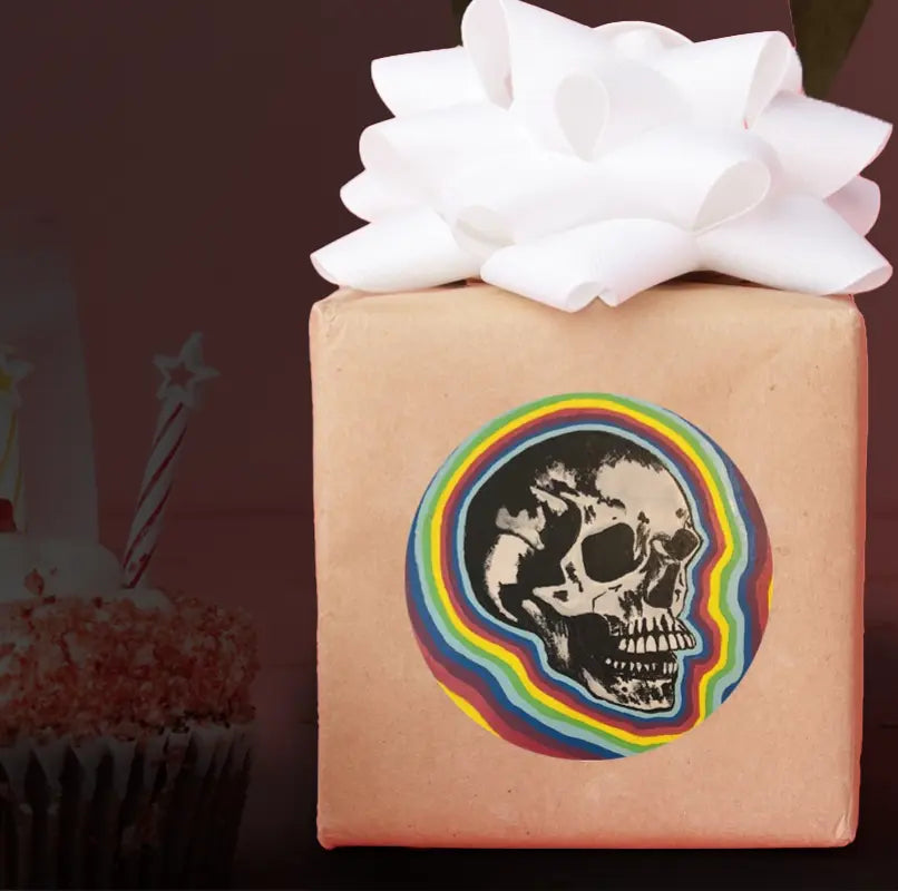 Larger sticker of a skull with rainbow around it, prototyped on the side of a wrapped gift. 